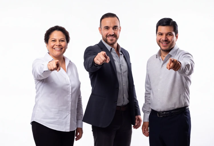 Dueño de negocio latino sonriendo con seguridad y señalando hacia adelante, invitando a agendar una consulta con Brandoval